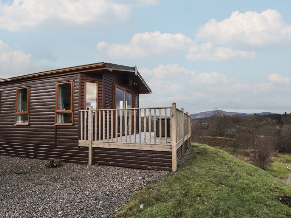 A log cabin with a deck and gravel at Coll in Fort William
