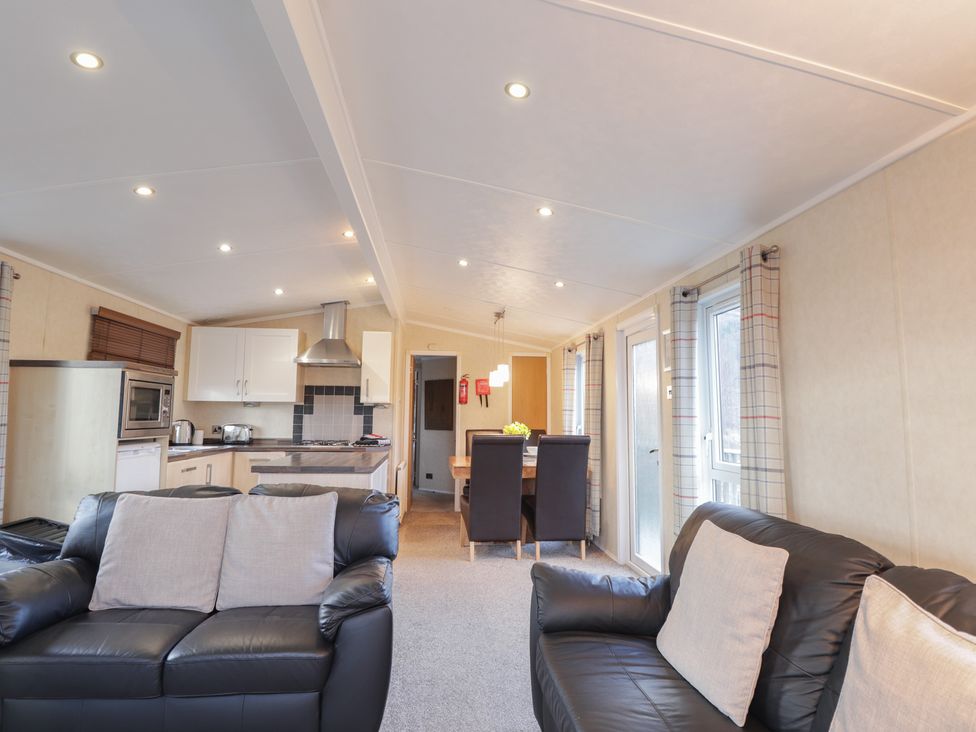 A living room with a sofa and dining area at Coll in Fort William
