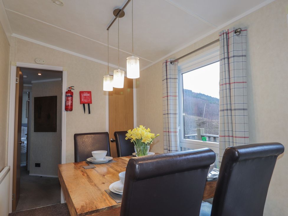 A dining room with a table and flowers in a vase at Coll in Fort William