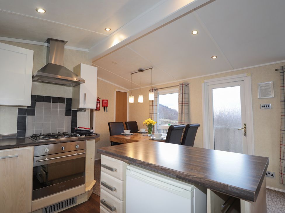 A kitchen with a stove and dining table at Coll in Fort William
