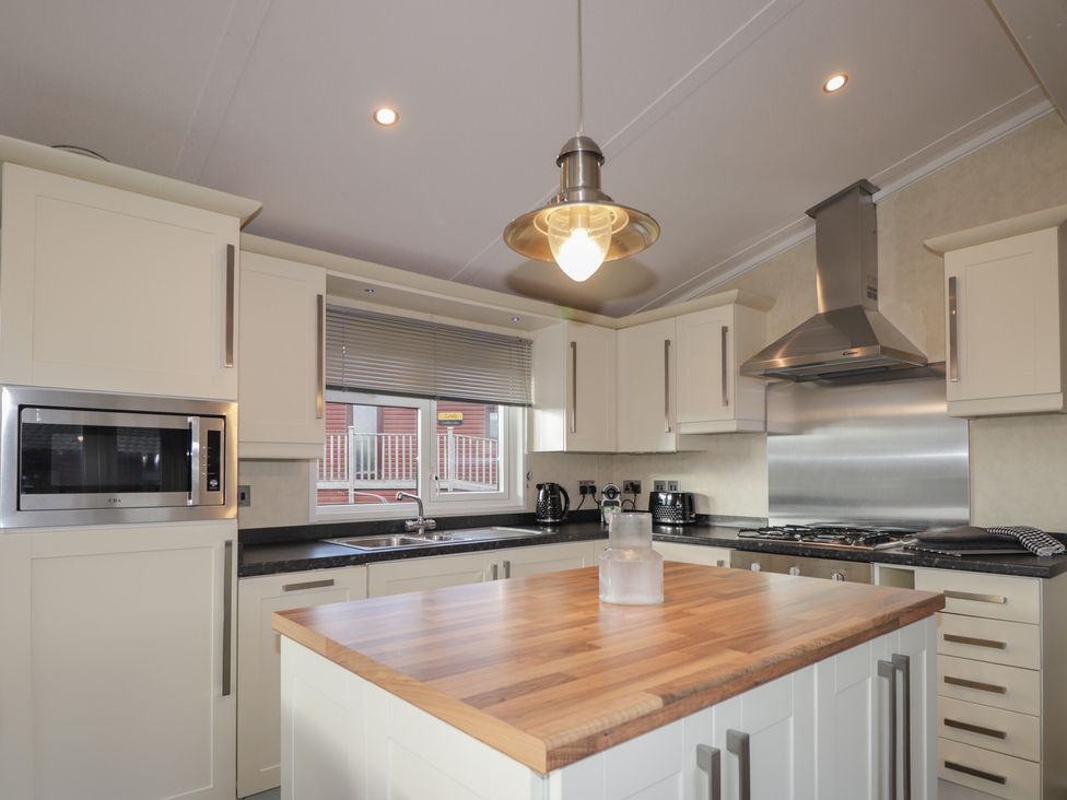 A kitchen with cabinets, stove, and island at Monach 3 Fort William
