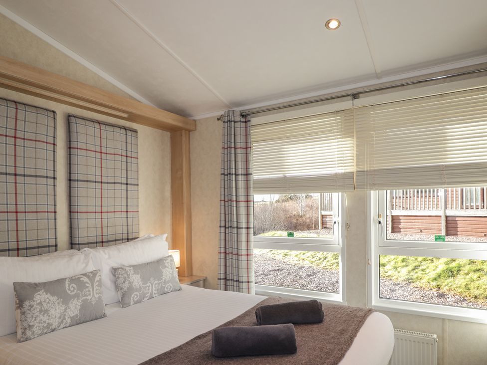 A bedroom with a bed and windows at Monach 3 in Fort William