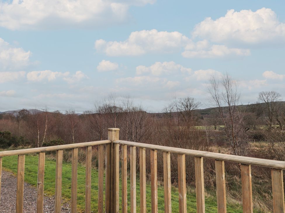 A view from a wooden railing overlooking grassy land and trees at Monach 3 in Fort William
