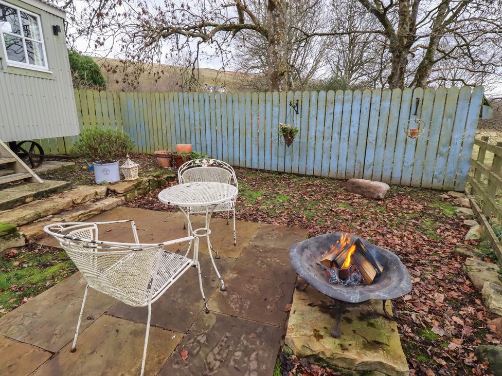 A garden with a fire pit and table with chairs at Woodland in Hexham