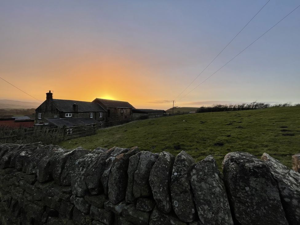 A house and field with a stone wall at The Farmhouse in High Peak