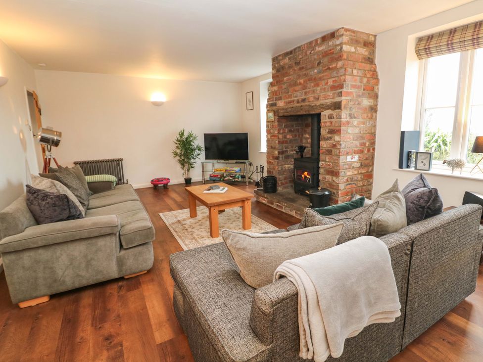 A living room with a sofa, coffee table, and fireplace at The Farmhouse in High Peak