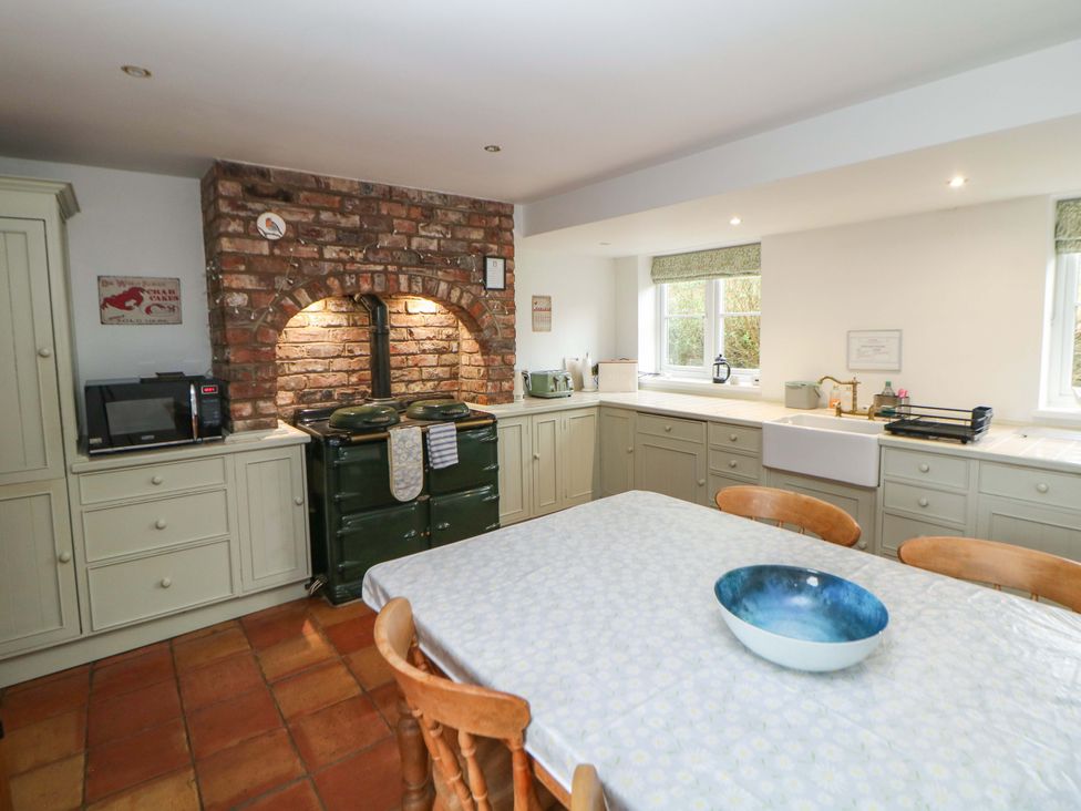 A kitchen with cabinets and a dining table at The Farmhouse in High Peak