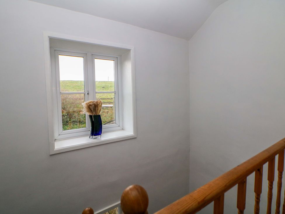 A staircase with a window and vase of dried flowers at The Farmhouse in High Peak