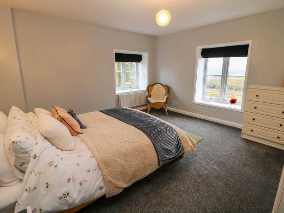 A bedroom with a bed and windows at The Farmhouse in High Peak