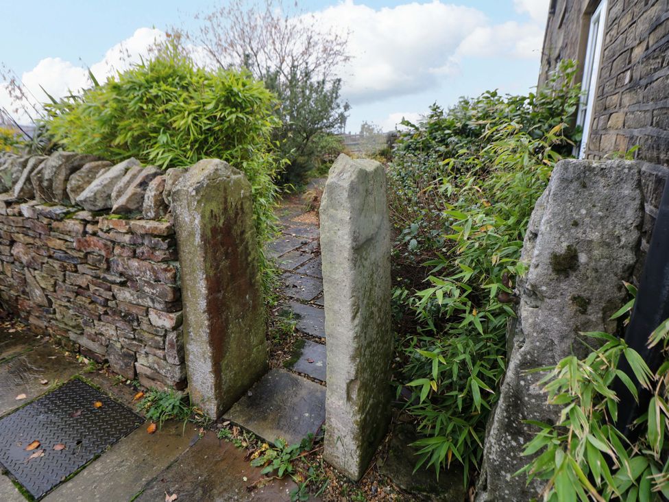 A stone gate and pathway surrounded by plants at The Farmhouse in High Peak
