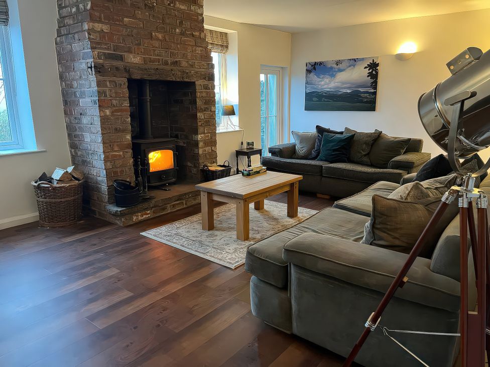 A living room with a fireplace, sofa, and coffee table at The Farmhouse in High Peak
