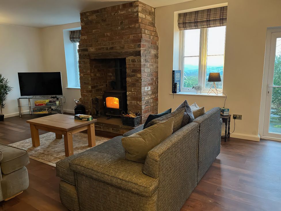 A living room with a fireplace and television at The Farmhouse in High Peak