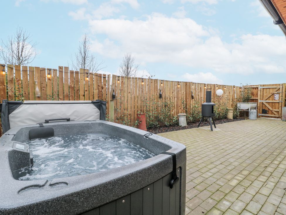 An outdoor area with a hot tub and a fence at The Sty in Hatton, Derbyshire