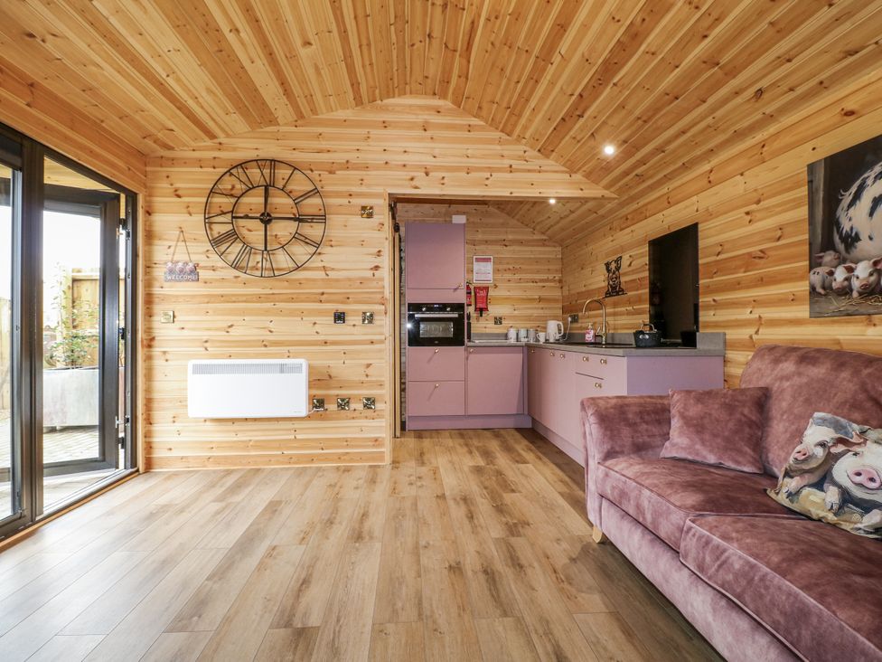 A living room with a sofa and kitchen unit at The Sty in Hatton, Derbyshire