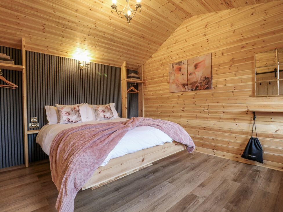 A bedroom with a wooden bed and shelves at The Sty in Hatton, Derbyshire