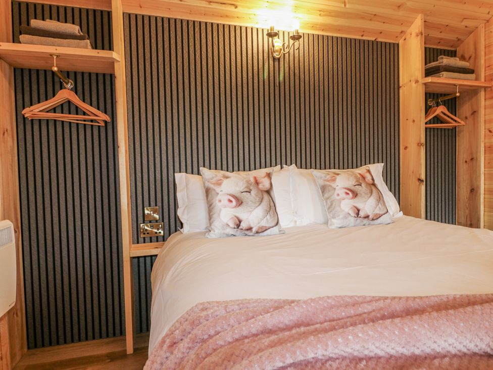 A bedroom with a bed and pig-themed pillows at The Sty, Hatton, Derbyshire