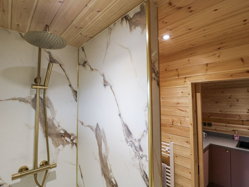 A shower with marble wall and wooden features at The Sty in Hatton, Derbyshire