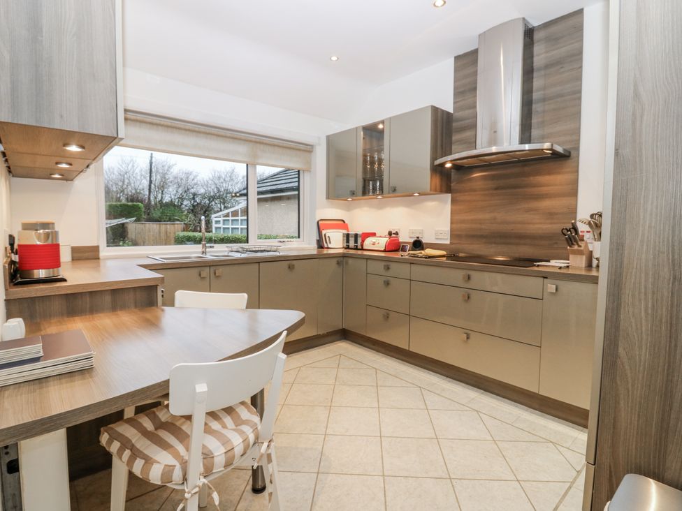 A kitchen with cabinets, sink and dining table at Cairndhu in Bossiney