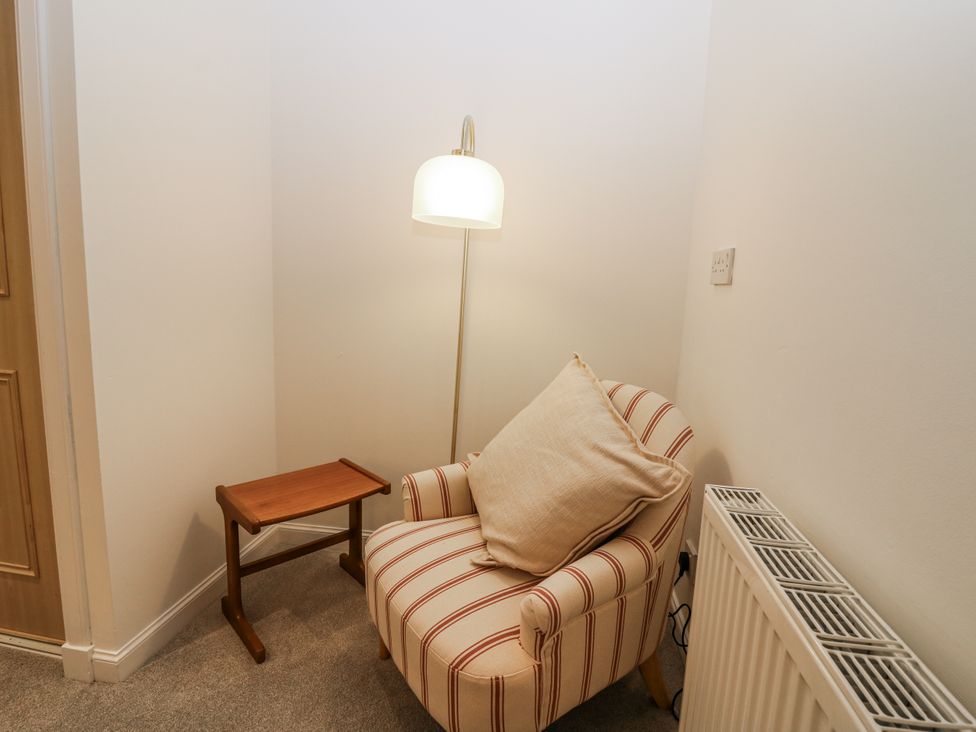 A sitting area with an armchair and a lamp at Cairndhu in Bossiney