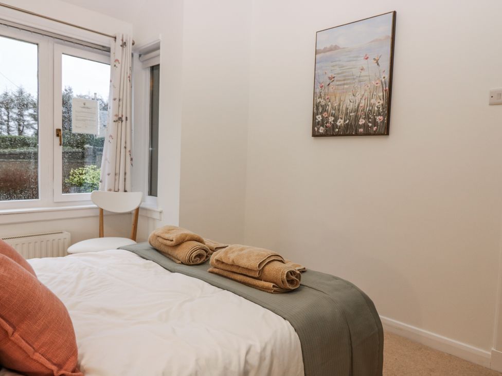 A bedroom with a bed, towels, chair, and a window at Cairndhu in Bossiney