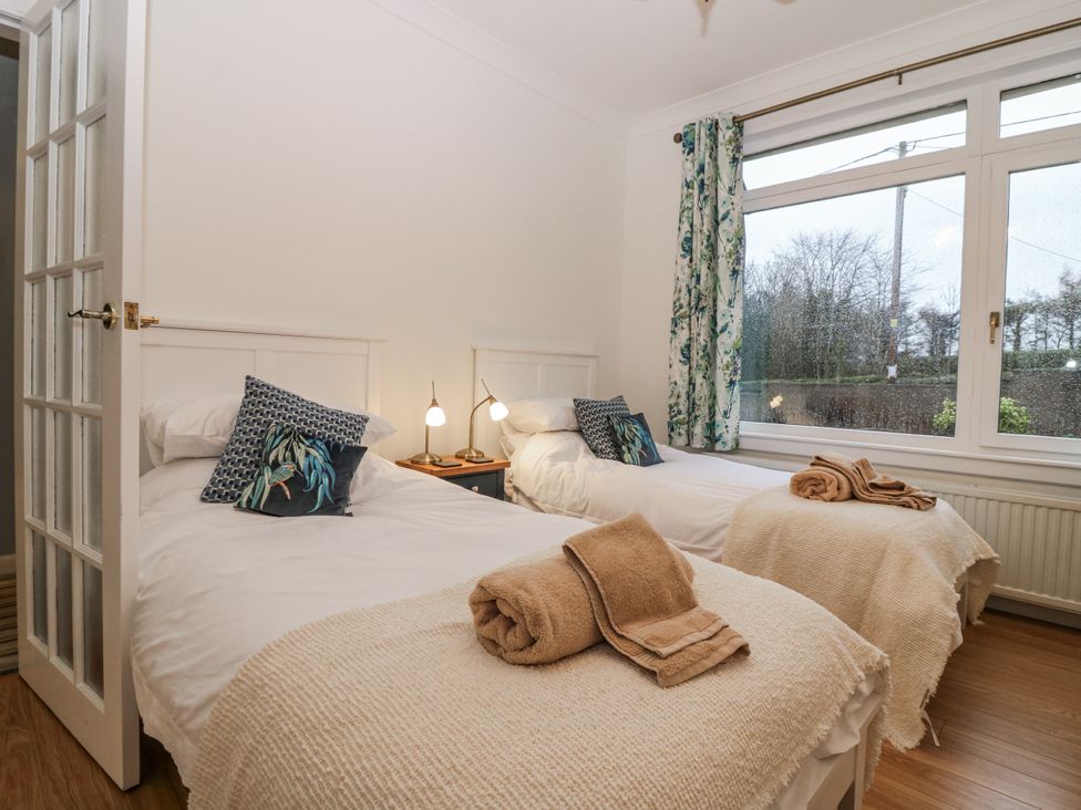 A bedroom with twin beds and a window at Cairndhu in Bossiney