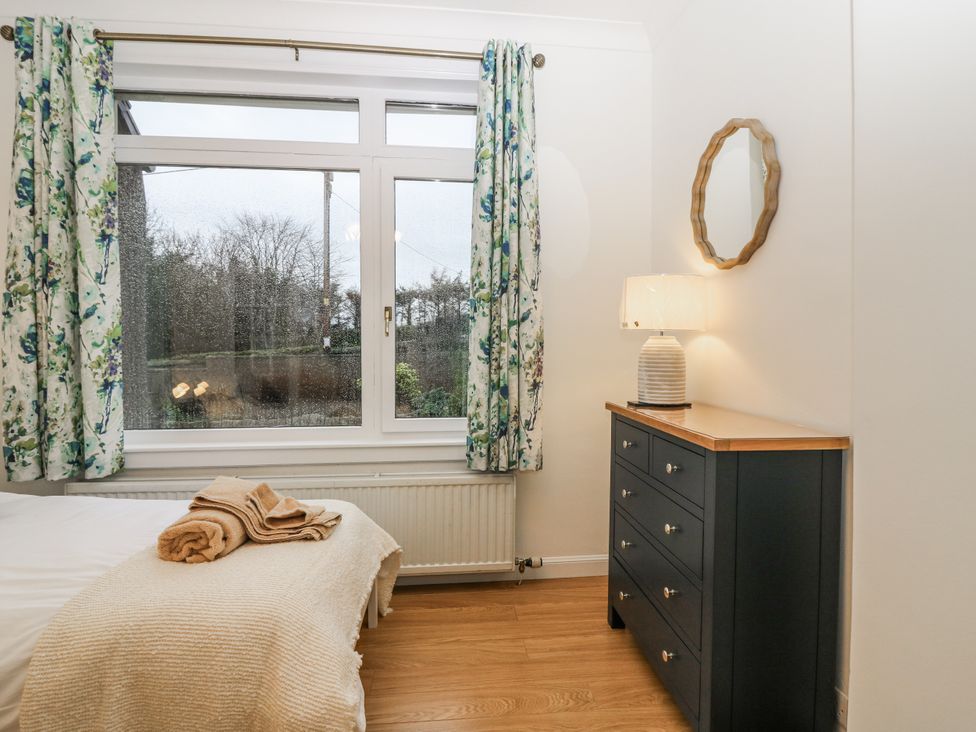 A bedroom with a window and dresser at Cairndhu in Bossiney