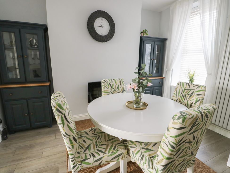 A dining room with a round table and patterned chairs at Bryn Y Mor in Beaumaris