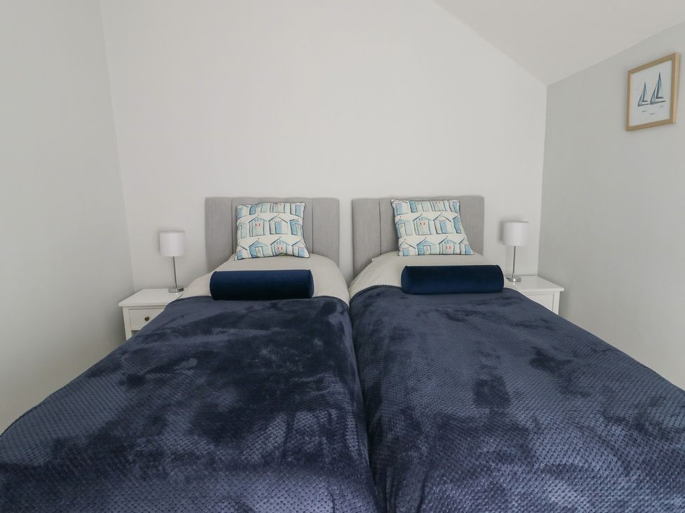 A bedroom with two beds and bedside tables at Bryn Y Mor in Beaumaris