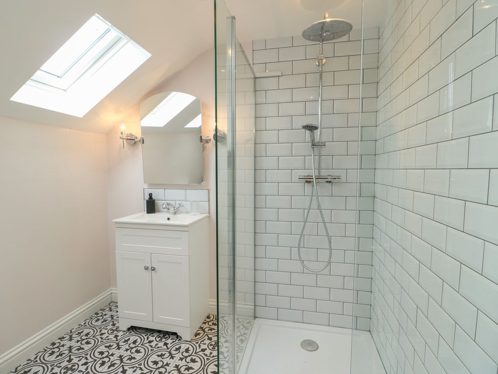 A bathroom with a shower, sink, and mirror at Bryn Y Mor in Beaumaris
