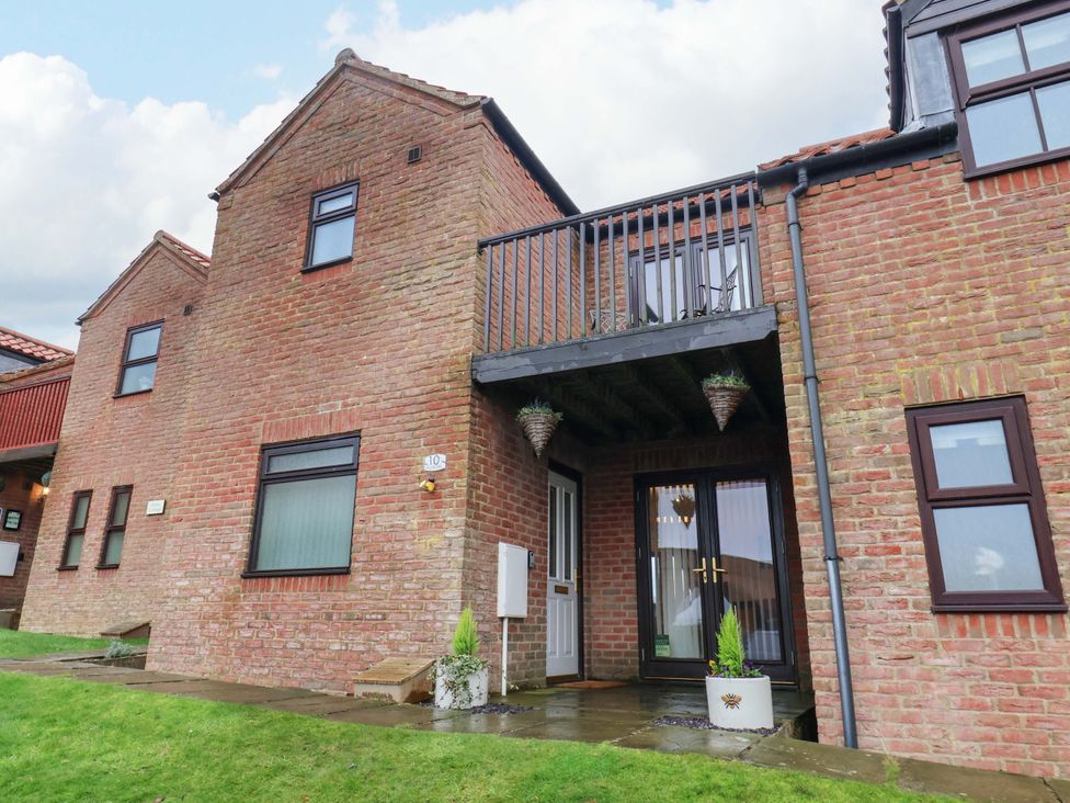An exterior view of a brick property with a balcony at Bumblebee Cottage in Whitby