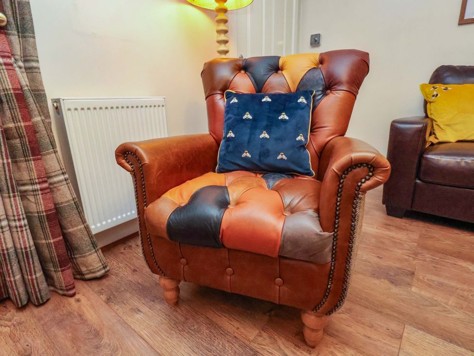 An armchair with a cushion next to a radiator at Bumblebee Cottage in Whitby