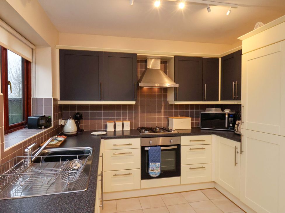 A kitchen with appliances and cabinets at Bumblebee Cottage in Whitby