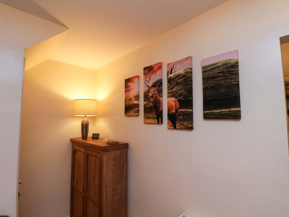 A hallway with a lamp and a wooden cabinet at Bumblebee Cottage in Whitby
