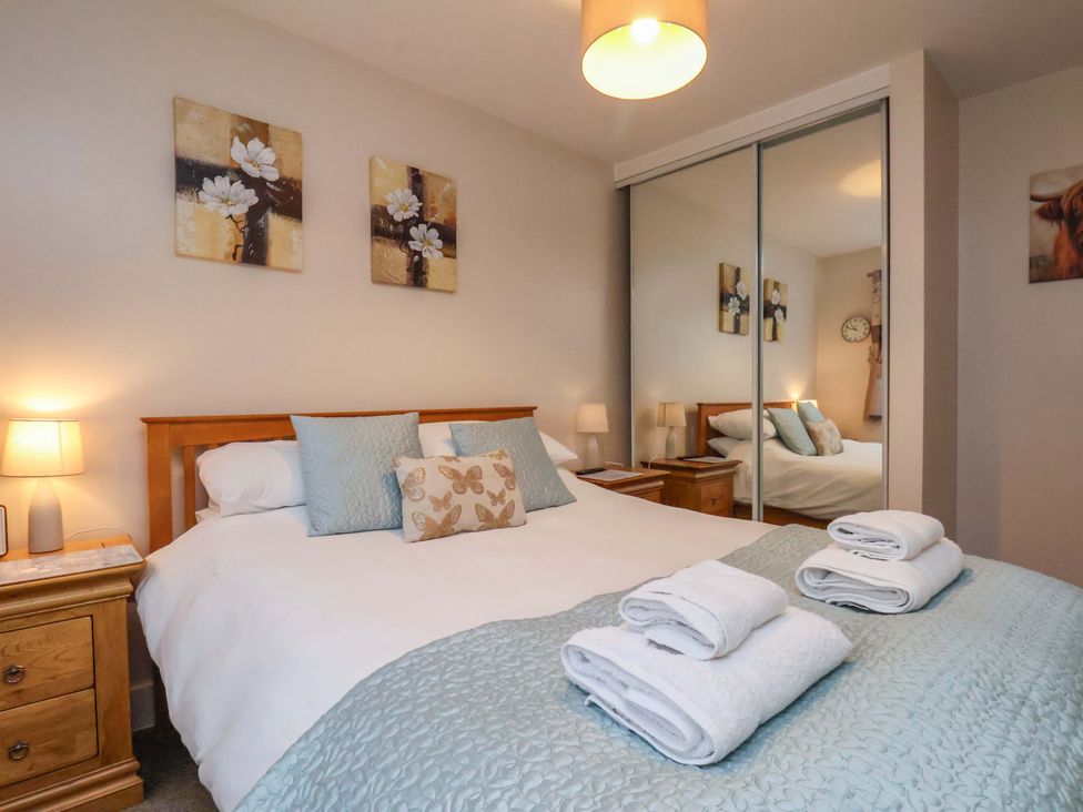 A bedroom with a bed, bedside tables, and artwork at Bumblebee Cottage in Whitby