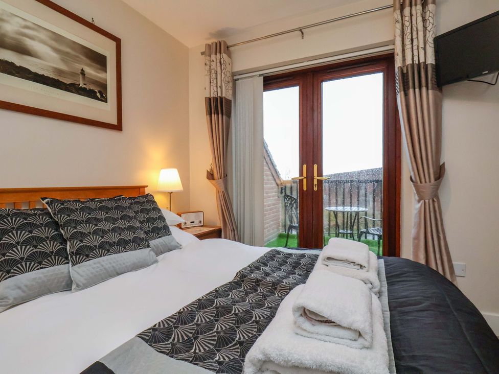 A bedroom with a bed and balcony access at Bumblebee Cottage in Whitby