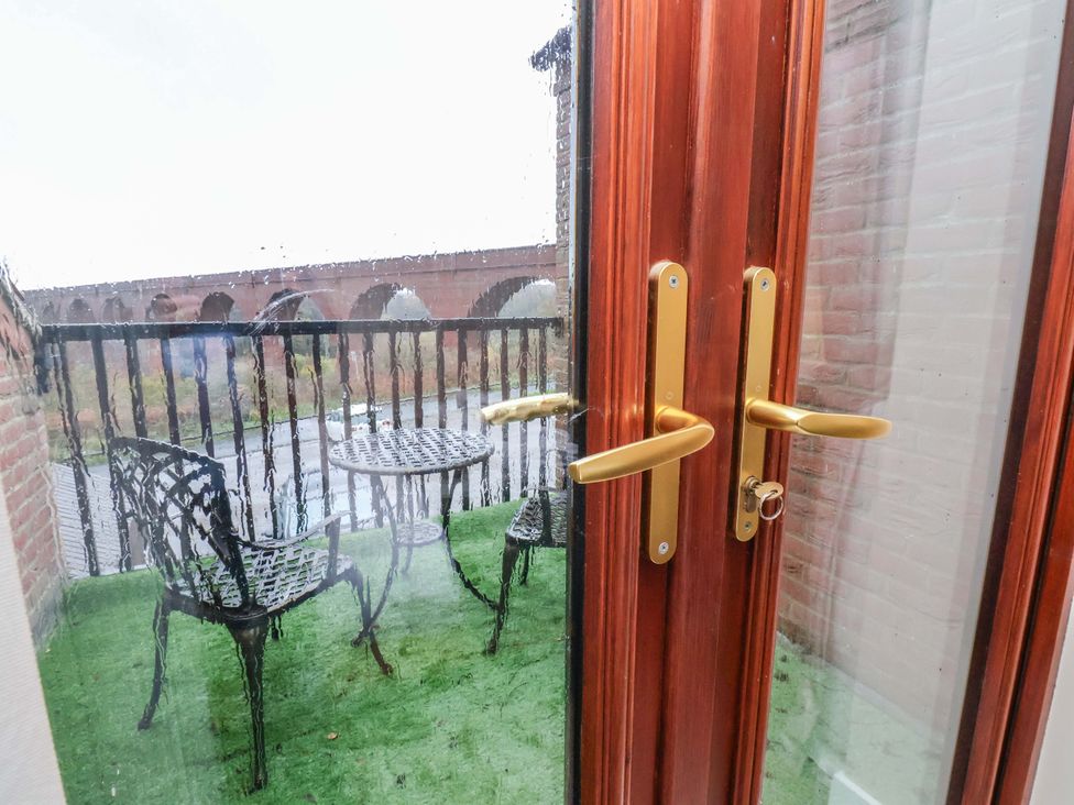 A balcony with table and chairs overlooking a river at Bumblebee Cottage in Whitby