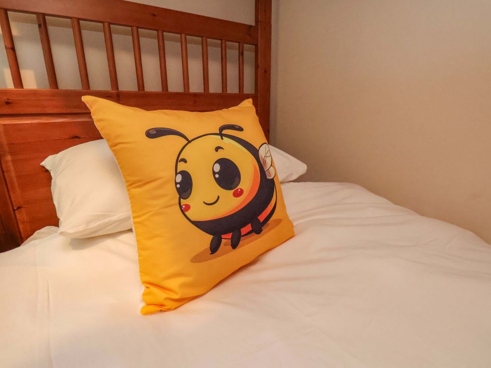 A bed with a bee-themed pillow at Bumblebee Cottage in Whitby