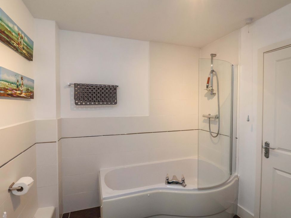 A bathroom with a bathtub and shower at Bumblebee Cottage in Whitby