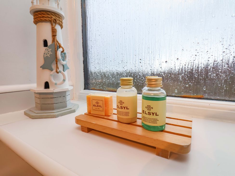 Bath products on a wooden shelf next to a lighthouse decoration at Bumblebee Cottage in Whitby