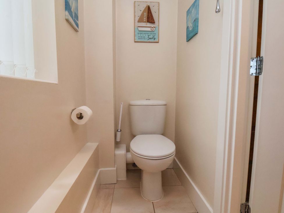 A bathroom with a toilet and wall art at Bumblebee Cottage in Whitby