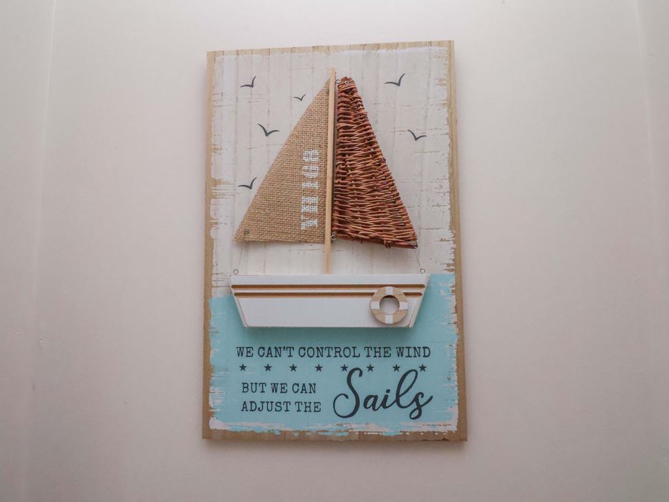 A decorative wall art featuring a sailboat and text at Bumblebee Cottage in Whitby
