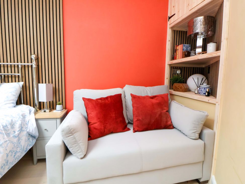A bedroom with a bed and a grey couch with red cushions at Skylights in Chester