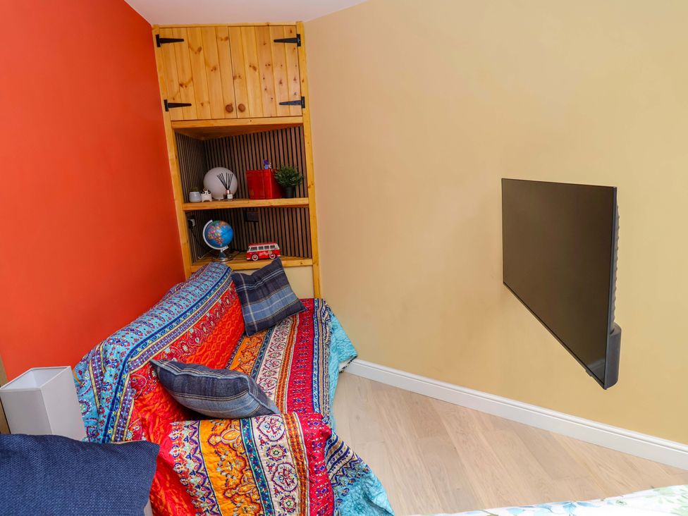 A living room with a sofa, shelves, and television at Skylights in Hoole