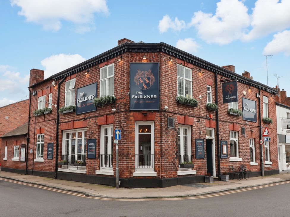 A pub exterior with signage and planters at The Faulkner in Hoole