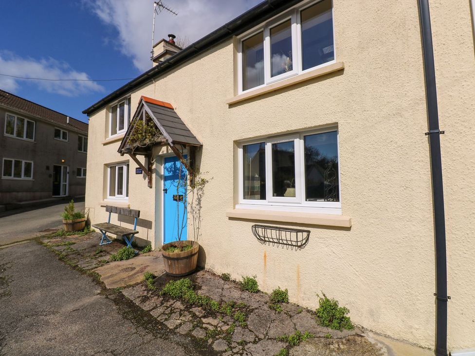 A house exterior with a blue door and a bench at 1 Mill Farm Cottages Narberth