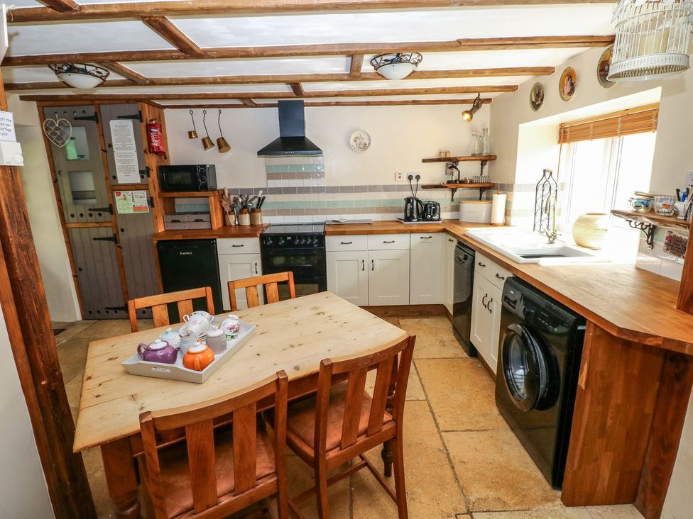 A kitchen with a dining table and appliances at 1 Mill Farm Cottages Narberth