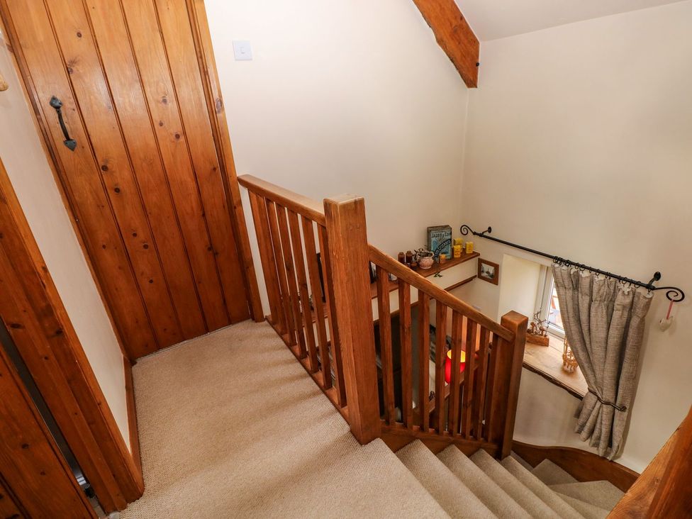 A staircase with a handrail and door at 1 Mill Farm Cottages Narberth