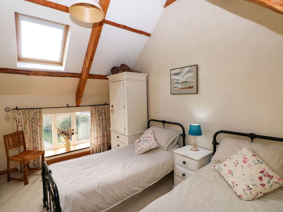 A bedroom with two beds and a window at 1 Mill Farm Cottages in Narberth