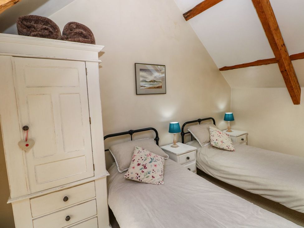 A bedroom with two beds and a wardrobe at 1 Mill Farm Cottages in Narberth