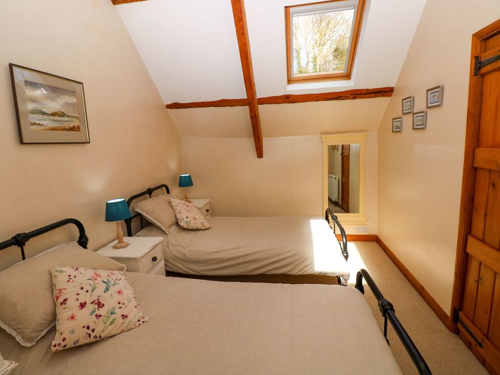 A bedroom with two beds and a mirror at 1 Mill Farm Cottages in Narberth